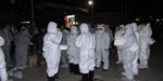 Thumbnail of Personal protective equipment worn by government workers assigned to cull poultry at a wet market in Huzhou city, Zhejiang Province, China, April 8, 2013. The protective clothing included ordinary disposable masks and latex gloves but not goggles or face shields.